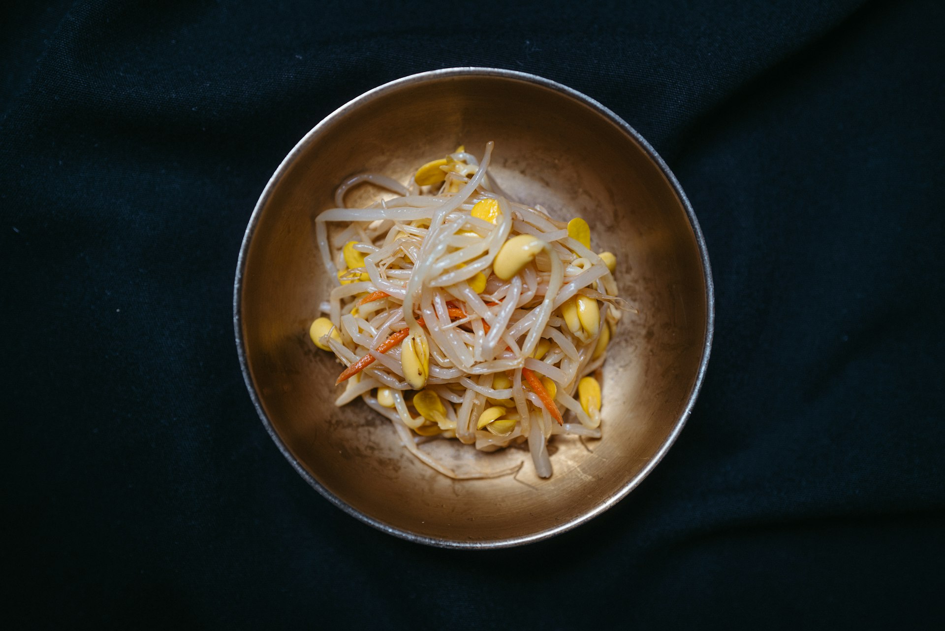 a metal bowl filled with food on top of a black table